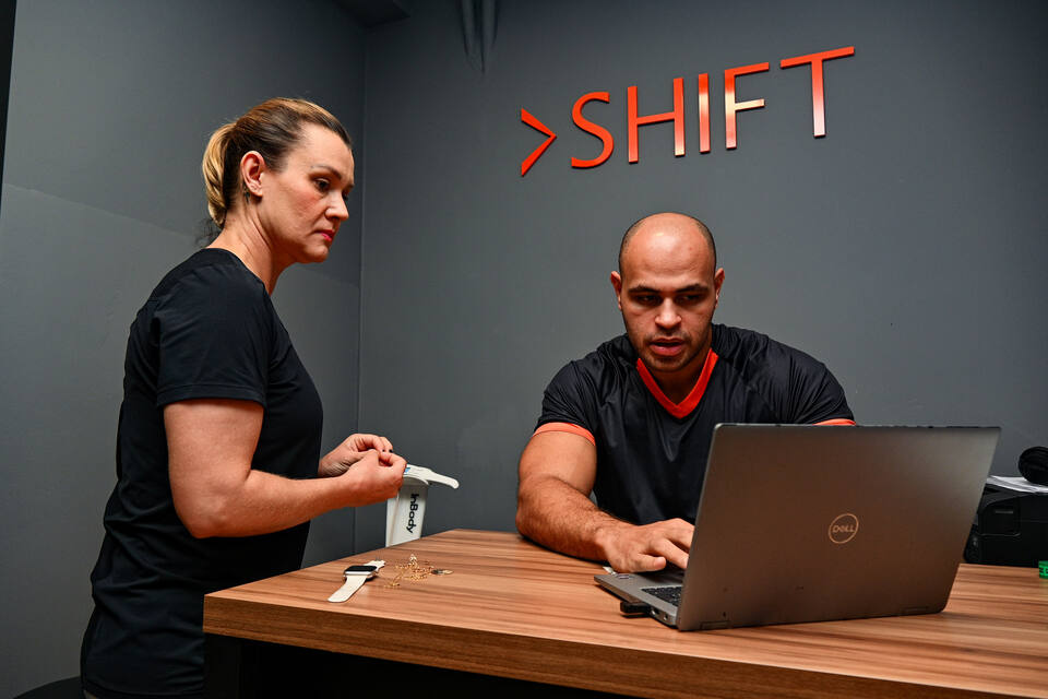 Profissionais da SHIFT em atendimento, diante do letreiro da SHIFT