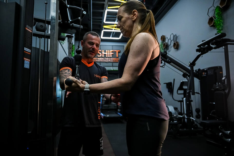Professor da SHIFT orientando uma aluna no salão de musculação